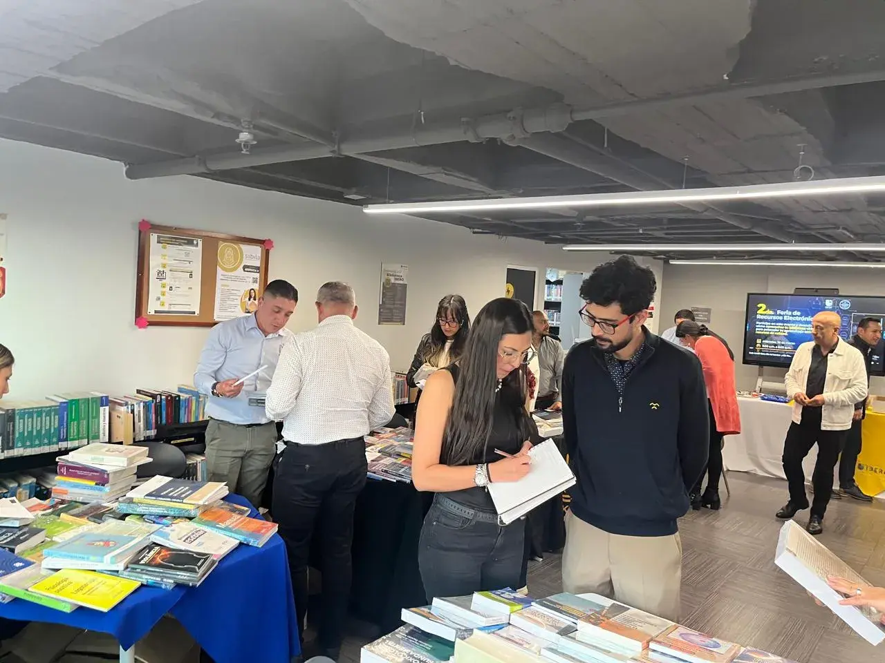 Docentes y proveedores en feria, revisando libros